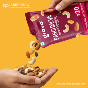 Hand pouring Grovo Panchmeva natural ingredients mix from a red snack packet into another hand, with almonds, cashews, and raisins falling against a yellow background.